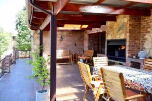 a patio with a table and chairs and a fireplace at Rawlingsons Country House in Dullstroom