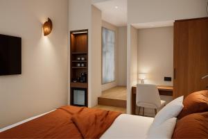 a bedroom with a bed and a desk with a chair at Hôtel de l'Horloge in Avignon