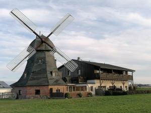 un vieux moulin à vent devant un bâtiment dans l'établissement Mühlenblick, à Brunshaupten