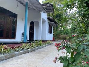 une maison blanche avec une porte et quelques fleurs dans l'établissement Femingo by Costels, à Hiriketiya