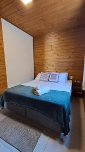 ein Schlafzimmer mit einem großen Bett mit einer Holzwand in der Unterkunft Pousada Encosta das Oliveiras in Imbituba