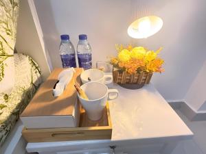 un comodino con una scatola, tazze e fiori di Flora Residence a Abu Dhabi Altre 43 foto