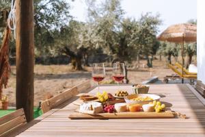 a table with two glasses of wine and food on it at Chão do Ribeirinho Country House in Atalaia