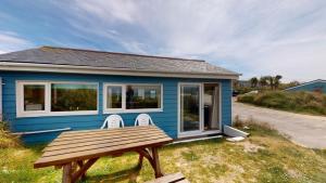 a blue tiny house with a bench in front of it at C37 Jupiter, Riviere Towans in Hayle