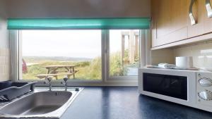 a kitchen with a sink and a large window at C37 Jupiter, Riviere Towans in Hayle