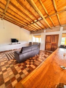 ein Wohnzimmer mit einer Ledercouch und einem Tisch in der Unterkunft Sítio Vista da Serra - Carrancas in Carrancas