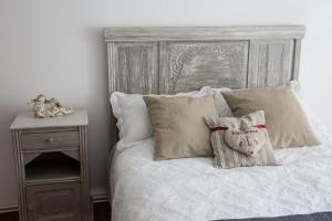 1 cama con cabecero de madera, almohadas y mesita de noche en Le coup de coeur en Coincy