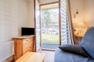 een woonkamer met een bank, een tv en een raam bij Studio Cabine Ax Les 3 Domaines in Ax-les-Thermes