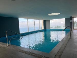 a swimming pool in a building with windows at Beautiful loft with ocean views in Reñaca in Viña del Mar