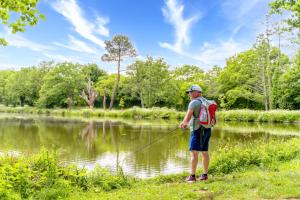 a man standing next to a river holding a fishing rod at Camping Capfun La Bretèche in Les Épesses