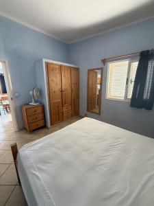 a bedroom with a large white bed and wooden cabinets at A casa do Amor in Vila do Maio