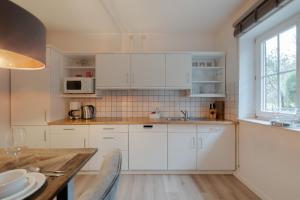 a kitchen with white cabinets and a table at DünenZeit in List