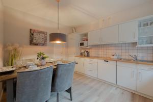 a kitchen with a wooden table and white cabinets at DünenZeit in List