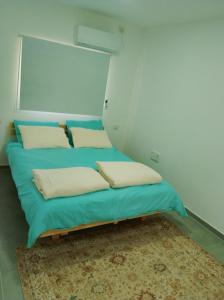 un letto in una camera con lenzuola e cuscini blu di אירוח משק 42 a Sheʼar Yashuv