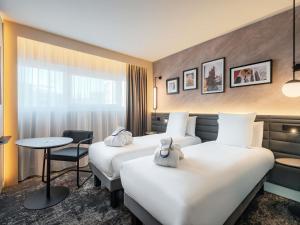 a hotel room with two beds and a table at Novotel Paris La Défense Nanterre in Nanterre +142 photos