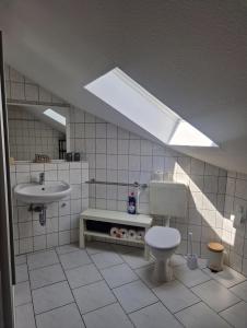 een badkamer met een toilet, een wastafel en een dakraam bij Ferienwohnung Thomée in Looft