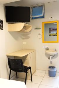 Un escritorio y una silla en una habitación con lavabo. en Esquina Batel - Hotel Econômico, en Curitiba 123 fotos más