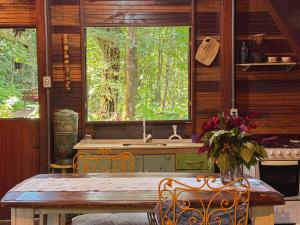 una cucina con tavolo, lavandino e finestra di Chalé Floresta Amada a Ouro Preto