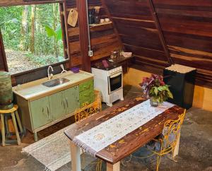 a kitchen with a table and a sink and a stove at Chalé na Floresta - 5min do Centro - Refúgio Natural in Ouro Preto