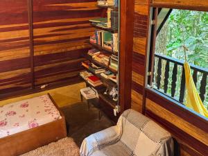 a room with a chair and a book shelf with books at Chalé na Floresta - 5min do Centro - Refúgio Natural in Ouro Preto