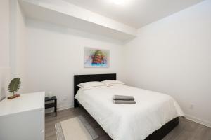 a white bedroom with a bed and a table at Buchanan 609 - Midtown Condo Luxe and Gym in Montréal +18 photos