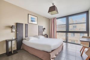 a hotel room with a bed and a desk and a window at Appart'hôtel Odalys City - Marseille Centre Parc Chanot Vélodrome in Marseille