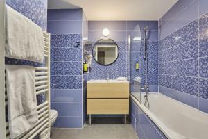 a blue tiled bathroom with a tub and a sink at Appart'hôtel Odalys City - Marseille Centre Parc Chanot Vélodrome in Marseille +60 photos