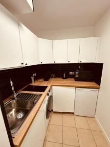 a kitchen with white cabinets and a sink at Modern and quiet apartment in Cergy