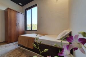 a bedroom with a bed and a window and flowers at Lake Side Mantra in Khamshet