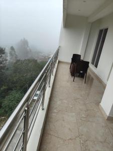 a room with a balcony with a chair and a view at Zeenus Holiday Resort in Yercaud