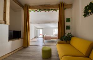 sala de estar con sofá amarillo y TV en Les Terrasses de Choubaka, en Alignan-du-Vent