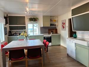 una cucina con tavolo con sedie rosse e una cucina con bancone di Mikkelsby house by Altafjord ad Alta