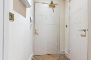 een hal met een witte deur en houten vloeren bij Leeds City Centre Luxe Flats 8 mins to Station! in Central Station