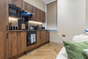 a kitchen with wooden cabinets and a stove at Leeds City Luxe Apartment with Parking, 8 mins to station! in Central Station