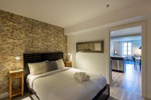 a bedroom with a bed and a stone wall at Les Immeubles Charlevoix - Le 1175 in Quebec City +7 photos