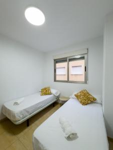 Dos camas en una habitación con ventana. en Apartamento San Diego 1 - Almyra Inmobiliaria, en Los Alcázares