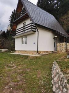 een wit huis met een zwart dak bij Vikendica Luka in Han Pijesak
