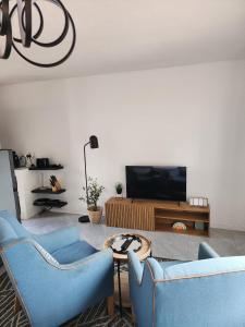 Una sala de estar con dos sillas azules y un televisor. en Lanina Harare Avenues Apartment, en Harare 6 fotos más