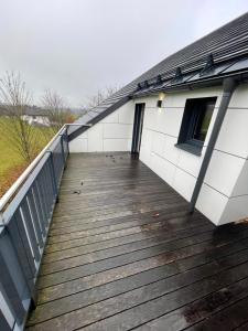 ein Holzsteg, der zu einem weißen Gebäude führt in der Unterkunft Moderne Maisonette-Ferienwohnung mit Dachterrasse, Waldblick & Parkplatz in Friedburg