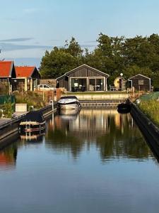 two boats are docked in a river with a building at Lauwershuisje, Sauna, Harbour Lauwersmeer in Anjum