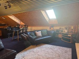 ein Wohnzimmer mit einer Ledercouch und einem Tisch in der Unterkunft The Loft in Lurgan