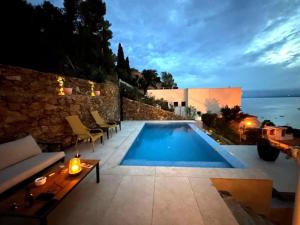 una piscina con sillas y un sofá en el patio en Preciosa casa con piscina desbordante y vistas al mar, en Roses