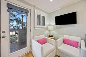 een woonkamer met 2 witte stoelen en een raam bij Oceanfront Sunrises on Mitchelville Beach in Hilton Head Island