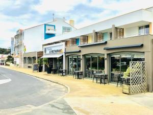 ein Gebäude mit Tischen und Stühlen vor einer Straße in der Unterkunft L'Espadon in Saint-Jean-de-Monts