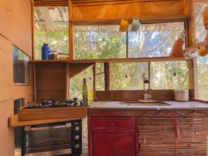 una cucina con un lavandino, un fornello e una finestra di Cabana Floresta Amada a Ouro Preto