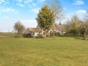 ein Haus inmitten eines Feldes mit einem Baum in der Unterkunft Rookery Cottage in Little Staughton + 11 Fotos