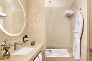 a bathroom with a sink and a mirror and a tub at NH Valencia Center in Valencia