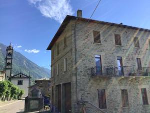 an old stone building with a clock tower on a street at Fuga dalla città in Grosotto