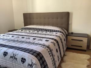 a bed with a black and white comforter and a night stand at Fuga dalla città in Grosotto
