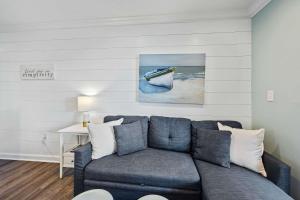 een woonkamer met een blauwe bank en een schilderij van een boot bij Unspoiled Beachfront Villa Sunrises from Balcony in Hilton Head Island